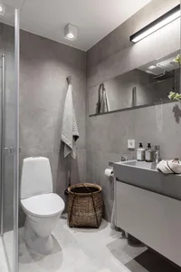 Modern bathroom with minimalist design, featuring concrete walls and floor, a floating vanity, and a walk-in shower.