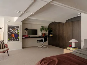A stylish modern bedroom featuring a sofa, wood cabinets, and a sleek desk area.