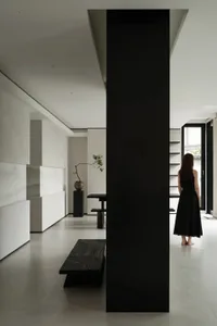 A modern living room featuring concrete walls, a black pillar, and a sleek, minimalist design.