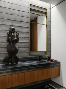 Modern industrial bathroom with concrete walls, black marble countertops, and wood accents.