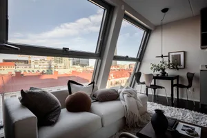 Modern living room featuring a white sofa, urban skyline, and large windows.