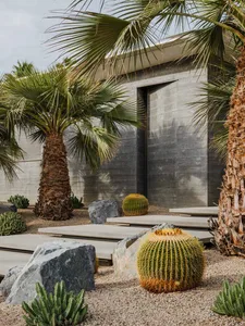 A modern landscape featuring concrete, gravel, and cactus plants.