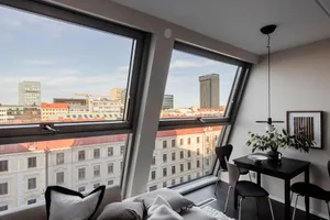 A modern living room featuring glass window frames with a cityscape view.