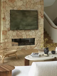 A modern living room featuring a stone fireplace and a flat-screen TV mounted above it.