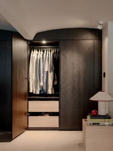Modern minimalist closet with wooden cabinets and hanging clothes.