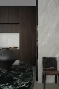A modern minimalist kitchen featuring a black marble countertop and a wooden chair.