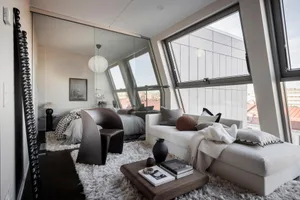 A modern minimalist living room featuring a white leather sofa, minimalist decor, and large windows with a view of the city.
