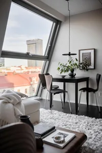Modern minimalist living room interior with white sofa, black table, and black chairs.
