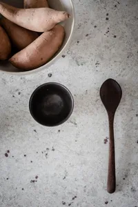 A simple food prep space with a wooden spoon and bowl placing on a textured surface.