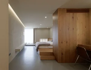 A minimalist bedroom with wooden walls and a bed on a wooden platform.