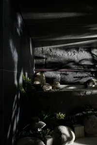 A minimalist concrete bathroom features natural light and rock elements.
