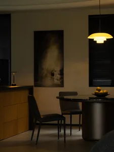 簡約餐廳內擺放黑色皮革餐椅與圓形餐桌，桌上擺放一碗水果。