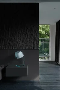 A modern bedroom featuring a glass lamp on a floating nightstand with a textured black wall in the background