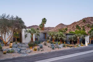 Modern house with concrete facade and palm trees in desert landscape