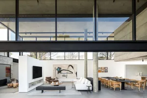 Interiored living room with concrete walls and floor, large windows, and minimalist furniture.