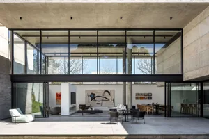 A modern interior living space featuring concrete walls and floors, large windows, and contemporary furniture.