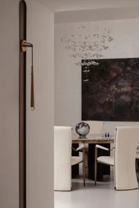 A modern dining room featuring a marble table and chandelier.