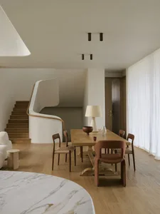 Modern dining room featuring a wooden table, marble accents, and stylish furniture.