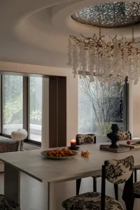 Modern dining room with a white table, chandelier, and chairs with floral upholstery.