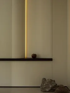 A minimalist wooden shelf with a single apple on it against a plain wall.