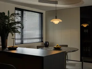 Modern kitchen with dark marble countertops, white walls, and black window blinds.