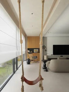 A modern living room featuring concrete flooring, wooden accents, and a leather swing.