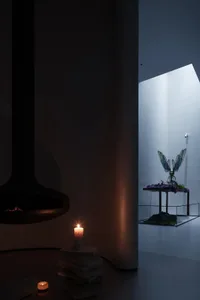 A modern living room featuring a glass window with a fire pit and candle.