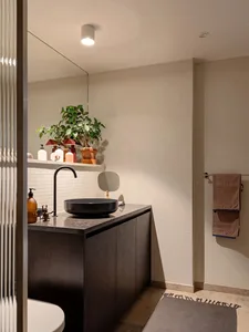 A modern minimalist bathroom featuring white tiles, a ceramic floor, and sleek fixtures.