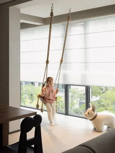 A child on a rope swing in a modern playroom setting.