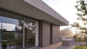 Modern residential exterior with concrete walls and large windows.