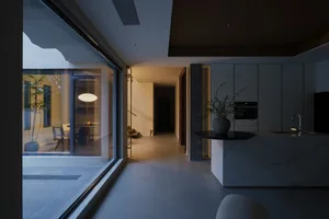 A spacious, minimalist residential kitchen featuring a modern design with clean lines and a prominent cement finish.