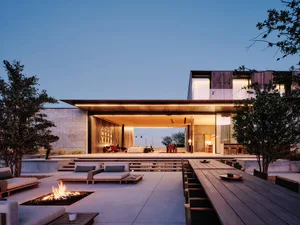 Modern stone exterior outdoor living space with seating and fireplace.