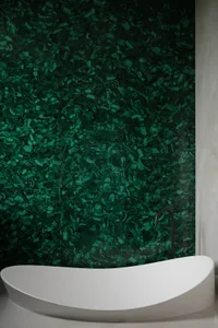 A modern bathroom featuring a green granite wall and a white oval-shaped bathtub.