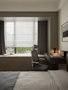 A modern bedroom featuring a wooden desk and fabric seating.