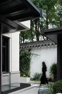 A modern exterior architectural design featuring concrete, glass, and greenery.