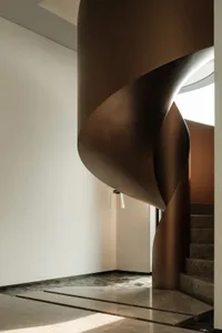 Modern interior featuring a metallic staircase with curved lines and a circular skylight.