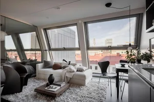 A modern living room with large glass windows, white furniture, and minimalist decor.
