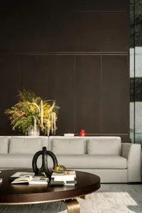 A modern living room with a beige sofa adorned with a large, vibrant flower arrangement and various decorative items on the c
