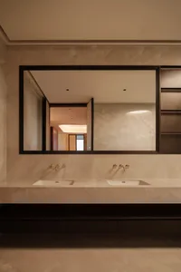 Modern bathroom with marble countertops and sinks, dual faucets, and a large mirror.