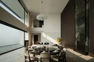 Modern minimalist dining room featuring a large round table surrounded by chairs, set with white tableware and glassware. The