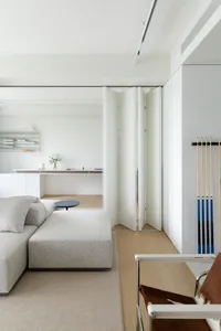 A modern minimalist living room featuring neutral textiles and wooden accents.
