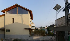 Modern residential exterior featuring a concrete facade, large windows, and a sloped roof.