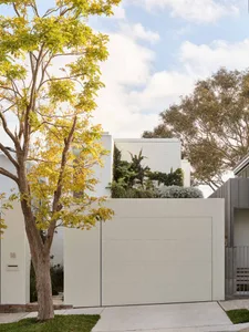 Modern residential exterior with metal cladding and large white gate