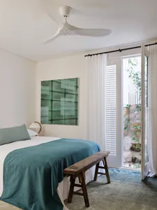 A minimalist bedroom with fabric bedding and wooden furniture.