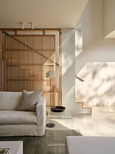 Minimalist living room featuring a wood-paneled wall and a white sofa with a patterned pillow.