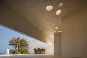 A modern architectural interior with concrete walls and circular light fixtures.