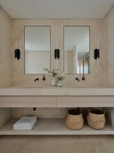 Modern bathroom with marble countertop, sinks, and wall sconces.