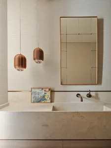 A modern bathroom with a stone countertop, mounted faucet, and a rectangular mirror above it.