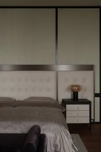 A modern bedroom featuring a white upholstered headboard made of contemporary furniture materials.