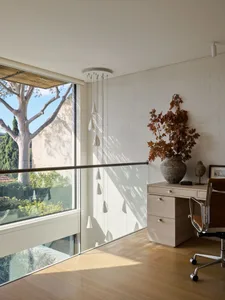 Modern home office featuring a wooden floor, a desk with a plant, and a large window.